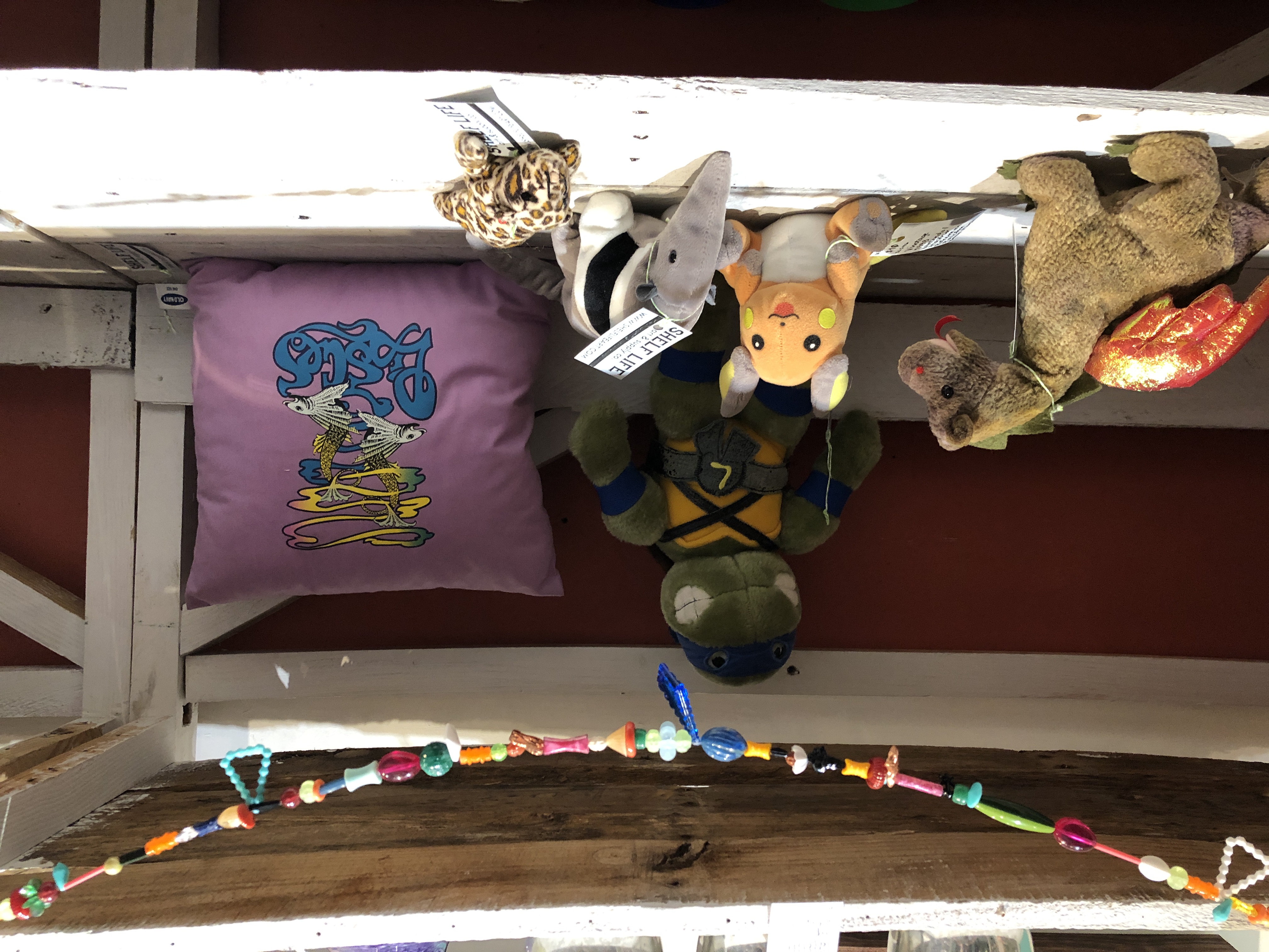 Vintage 1990s and Early 2000s plush items including Beanie Babies, McDonald's Teenie Beanie Babies, Teenage Mutant Ninja Turtles, Pokemon, and an Old Navy Pisces Zodiac throw pillow in Shelf Life Satellite at Design Archives Greensboro, NC.